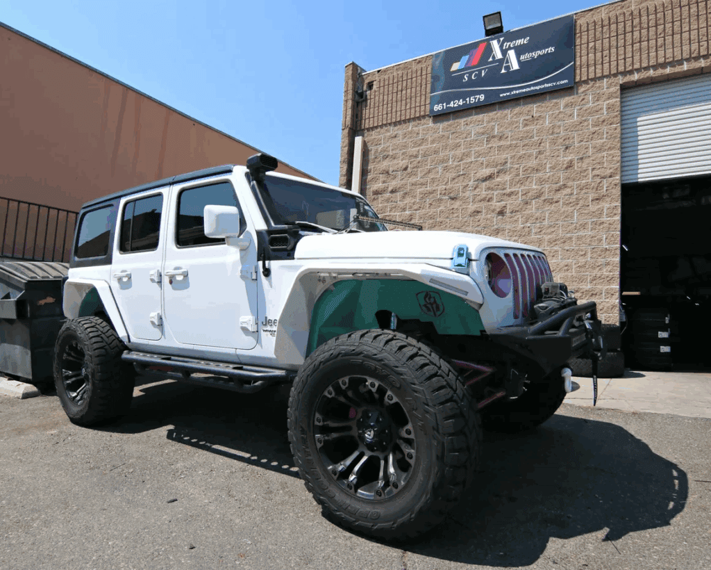 White Jeep Wrangler off-road vehicle parked outside auto sports shop.