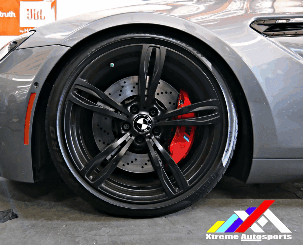 High-performance BMW wheel with red brake caliper and drilled rotor at auto shop.
