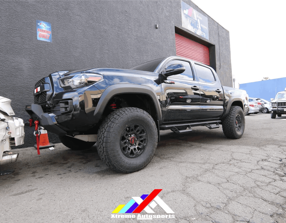Black off-road pickup truck parked near building at car dealership.